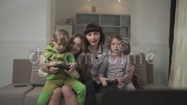 快乐的姐姐和快乐的<strong>小朋友</strong>坐在沙发上在客房里玩电子游戏。 欢乐家庭